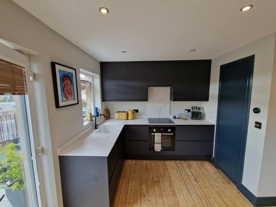 a kitchen with black and white cabinets and a wooden floor at Beach front apartment in Edinburgh