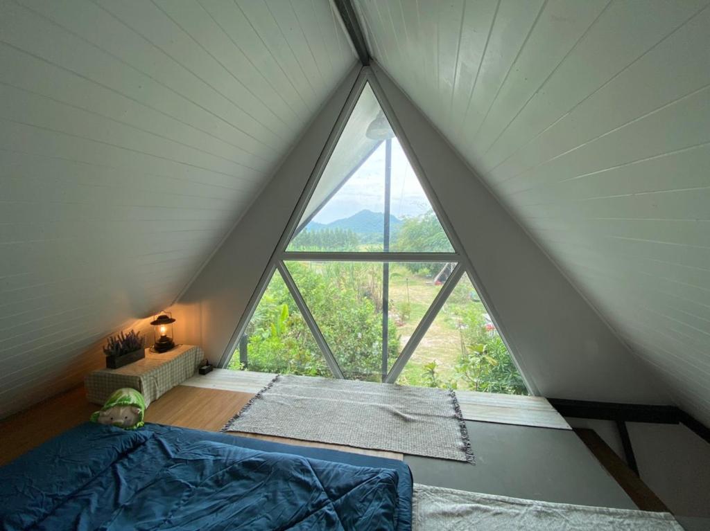 Bett in einem Zimmer mit einem großen Fenster in der Unterkunft Royal mountain view Ratchaburi in Ratchaburi