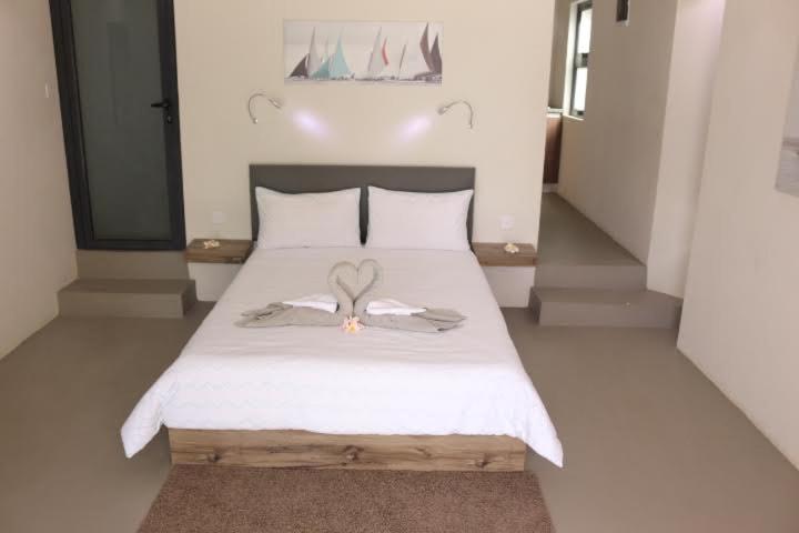 Un dormitorio con una cama blanca con alas de ángel. en Valmarin Seafront Apartments, en Trou d'Eau Douce