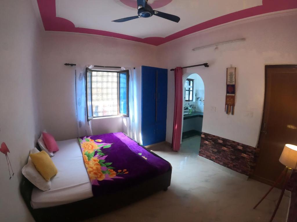 een slaapkamer met een bed en een plafondventilator bij Hobbit House Hostel in Rishīkesh