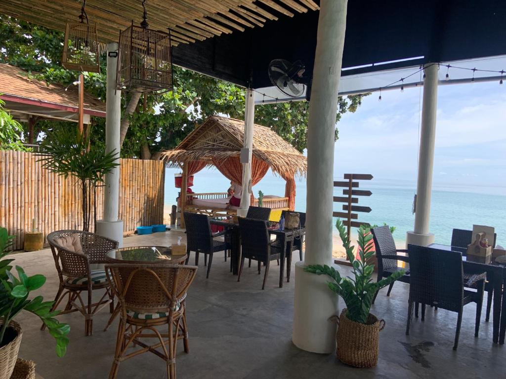 a restaurant with tables and chairs and the ocean at 4U Resort Samui in Lamai