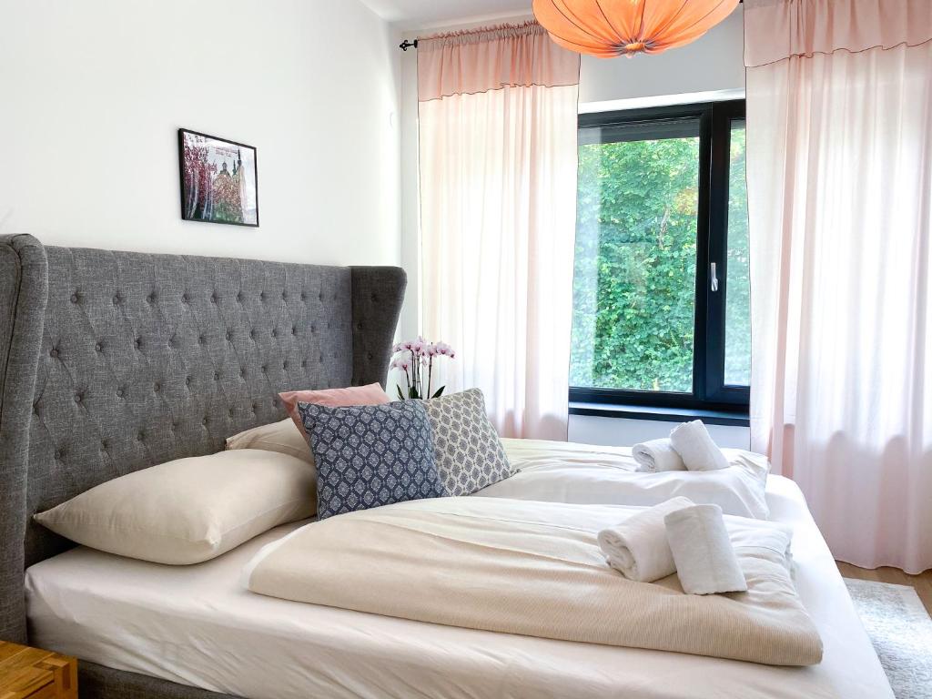 ein Bett mit weißer Bettwäsche und Kissen in einem Schlafzimmer in der Unterkunft Apartment Aria Velden in Velden am Wörthersee