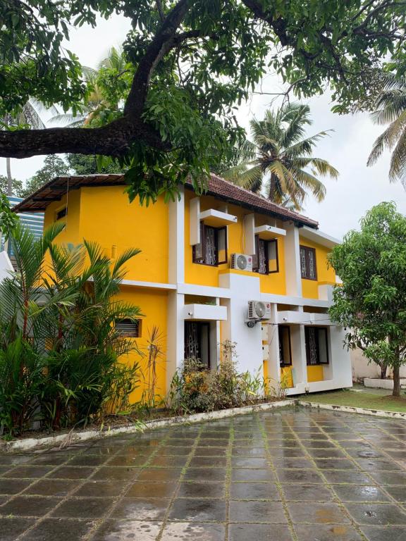 uma casa amarela e branca com um pátio em Mother's Inn Homestay em Cochin