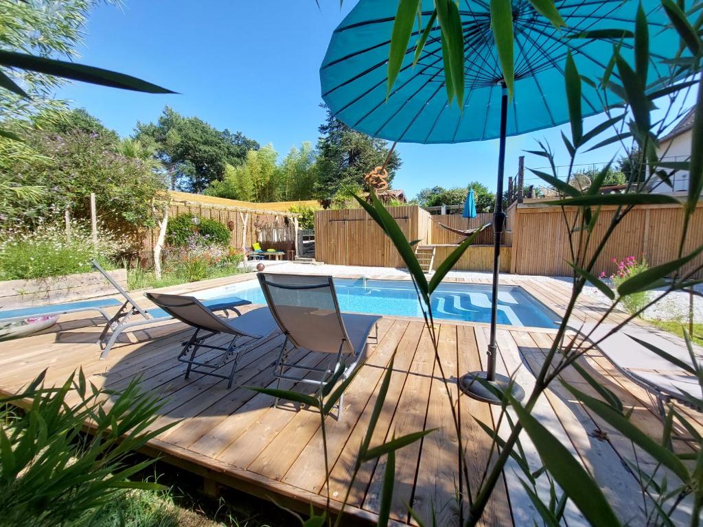 a deck with two chairs and an umbrella next to a pool at Villa Hossegor- Classée 4 étoiles, 6 chambres - 5 salles de bains - piscine chauffée 5 mn des plages in Hossegor