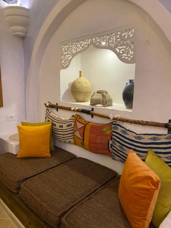 a room with colorful pillows and a shelf with vases at Hôtel Djerba Authentique - Au centre de Midoun in Midoun