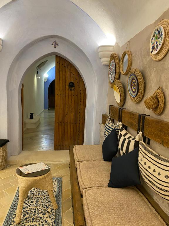 a living room with a couch and plates on the wall at Hôtel Djerba Authentique - Au centre de Midoun in Midoun