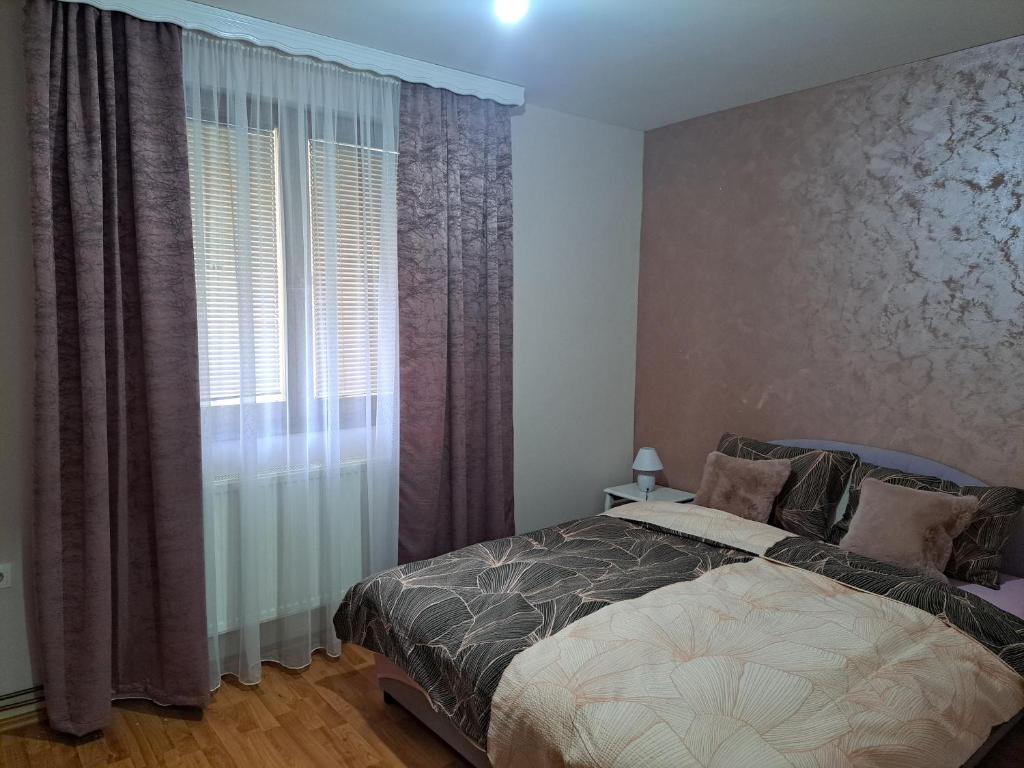 a bedroom with a bed and a window with curtains at Apartman Lara 2 in Foča