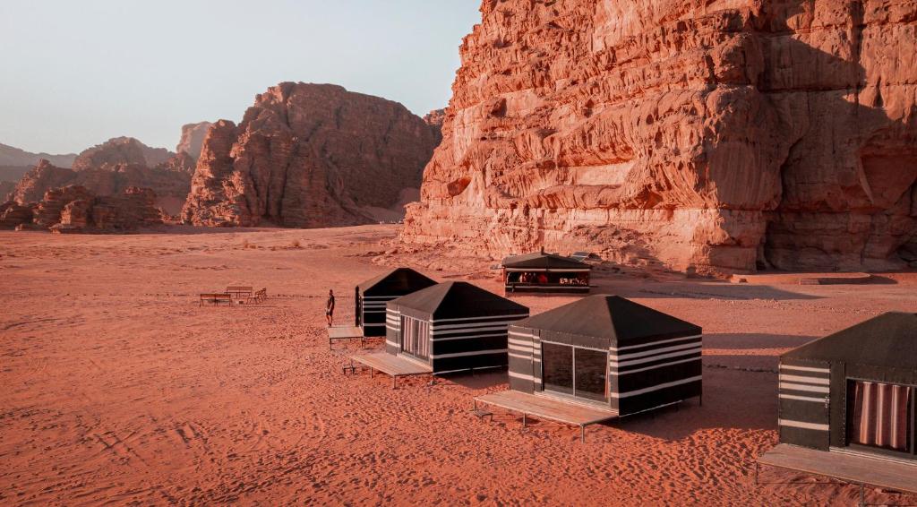 Un groupe de huttes dans le désert près d'une falaise dans l'établissement Desert Bird Camp, à Wadi Rum