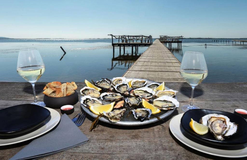una mesa con un plato de ostras y copas de vino en Charmante suite romantique avec cave à vin, en Cournonsec