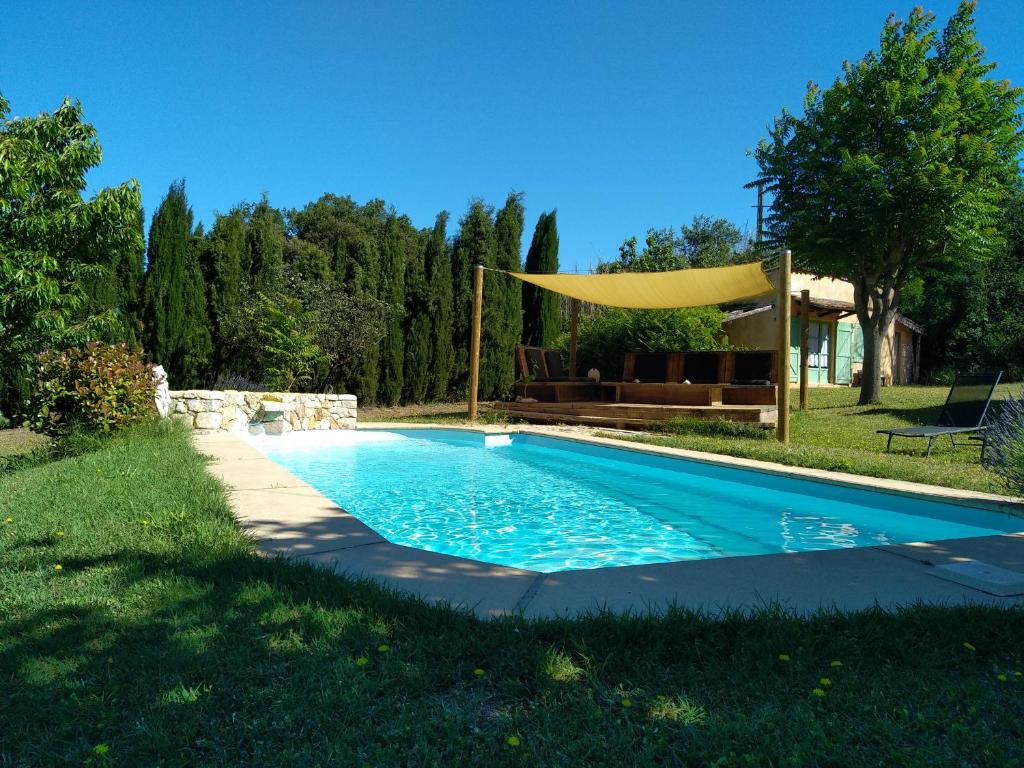 a swimming pool in a yard with a yellow canopy over it at VILLA 14 personnes in Pontevès