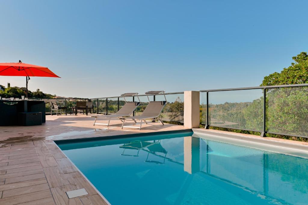 una piscina con sillas y sombrilla en Villa à l'entrée de Porticcio - Piscine - Vue dégagée, en Cauro