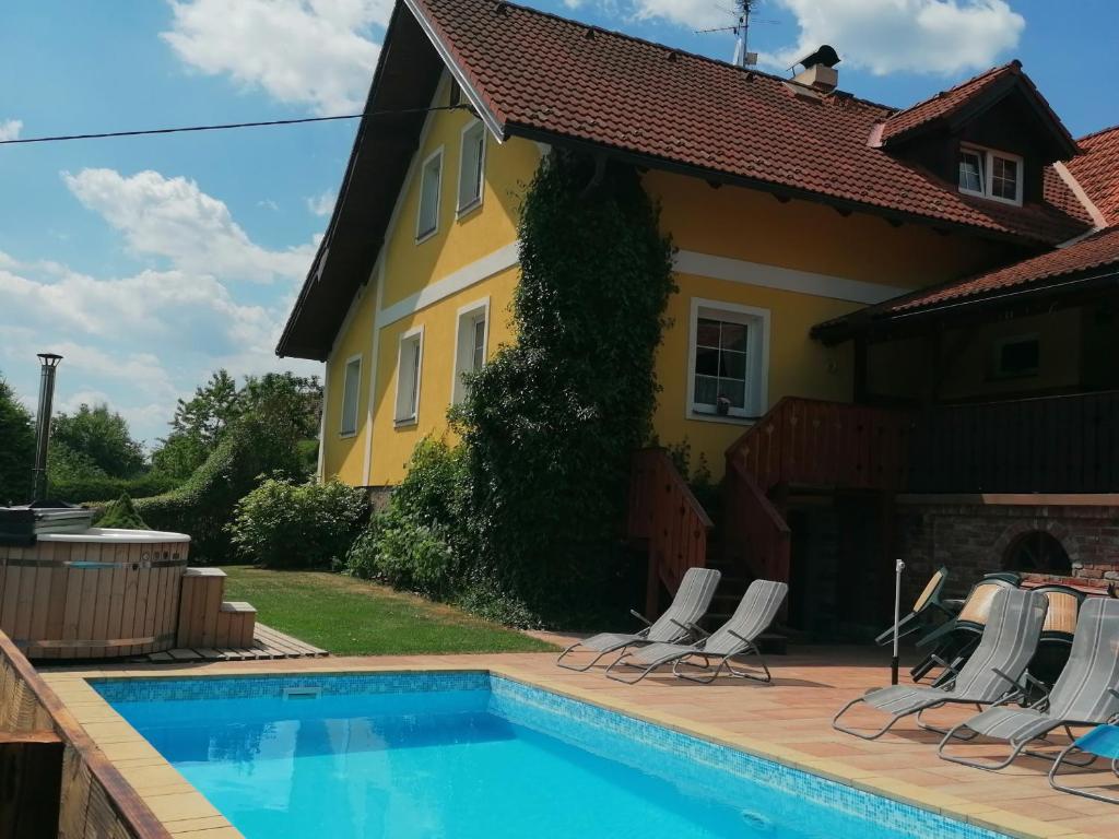 a pool in front of a house with chairs at Chalupa Dana in Víchová nad Jizerou