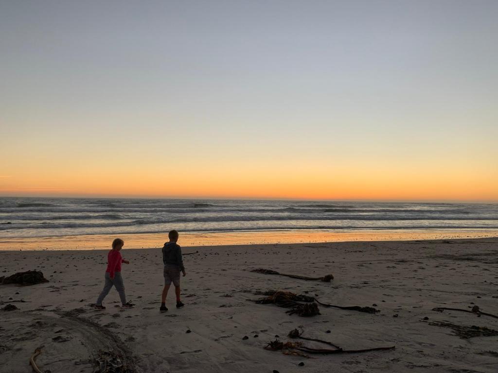 two people walking on the beach at sunset at Strandfontein holiday house in Strandfontein
