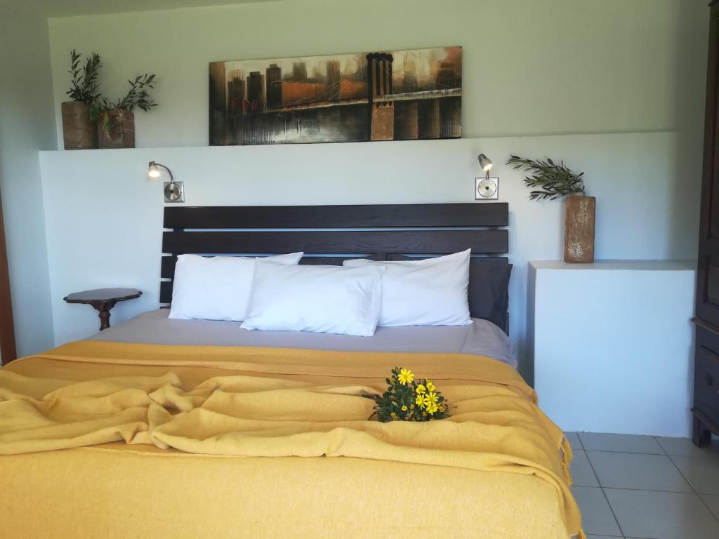 Una cama con una manta amarilla y flores. en Crossroads Guestrooms en Gordonʼs Bay