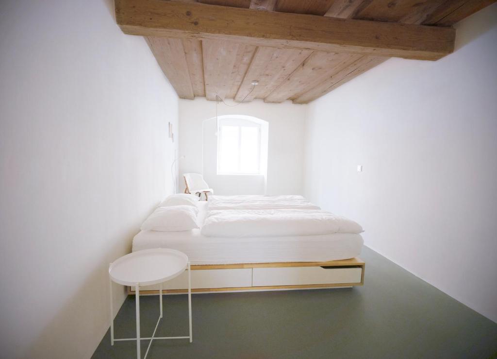una camera bianca con letto e sgabello di HERZIGE WOHNUNG IN ALTEM GEMÄUER a Linz