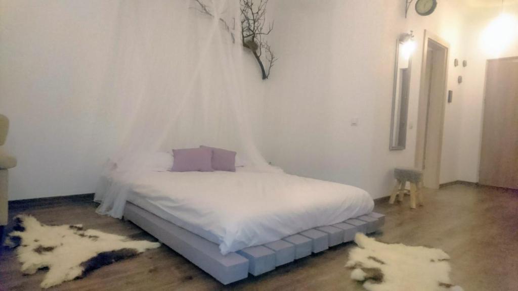 a bedroom with a white bed with white sheets and two rugs at Cluj City Iris Appartment in Cluj-Napoca