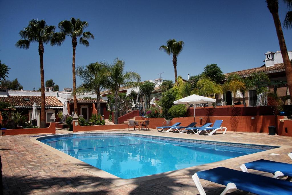 a swimming pool with chairs and palm trees at Quinta dos Amigos in Almancil