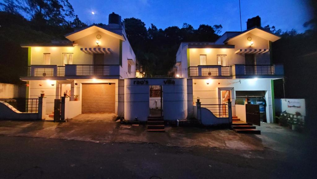a large white house with lights on it at night at Royal Black Pepper Cottage in Yercaud
