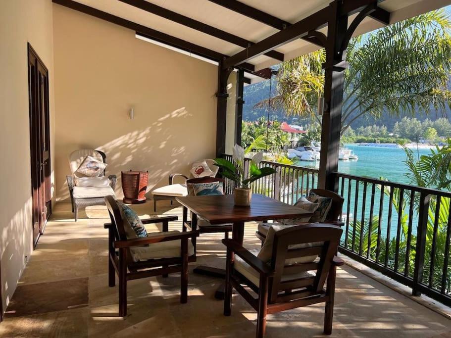 a dining room with a table and chairs on a balcony at Waterfront Maison by Simply-Seychelles in Eden Island