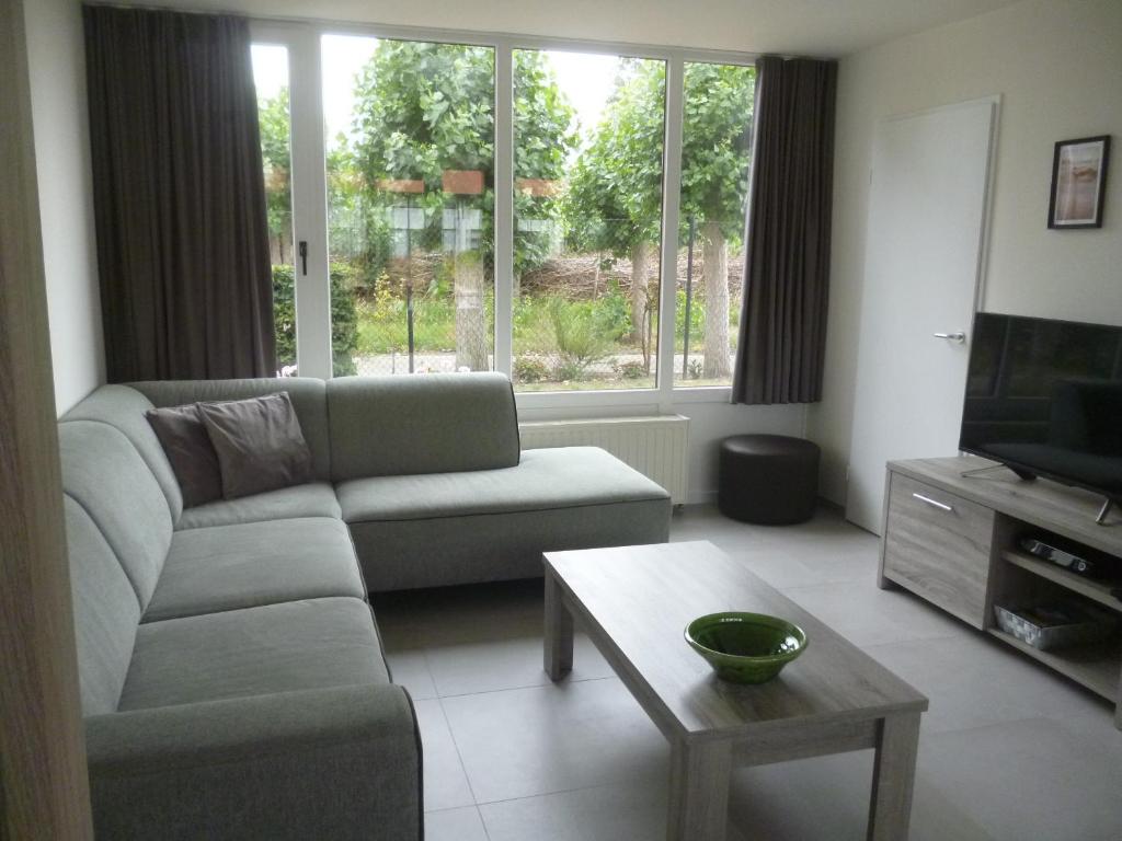 een woonkamer met een bank, een tv en een tafel bij Vakantiewoning De Zandkorrel in Middelkerke