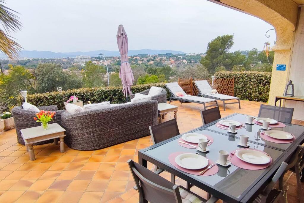 un patio avec une table, des chaises et un canapé dans l'établissement Belle villa avec vue imprenable., à Fréjus