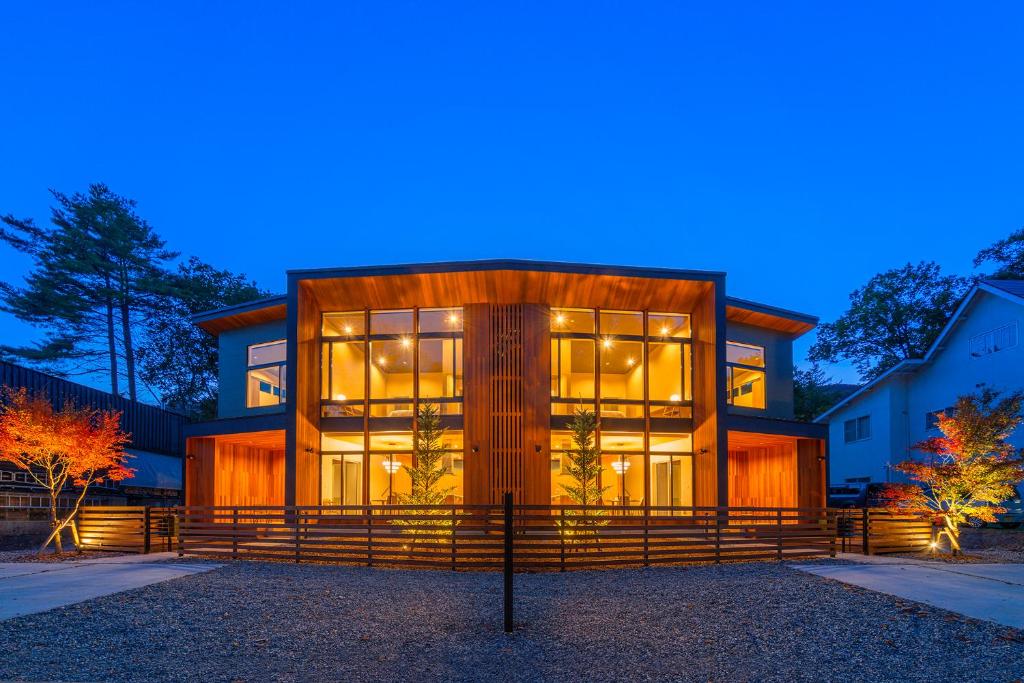 una casa con grandes ventanas de cristal por la noche en Ren chalet en Hakuba