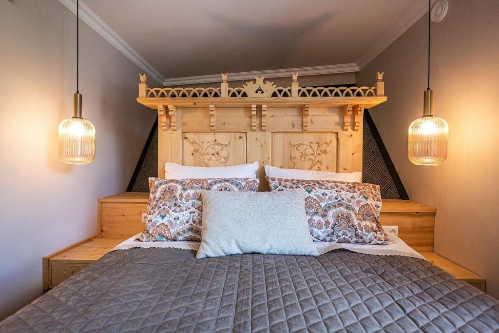 Un dormitorio con una cama con cabecero de madera y almohadas. en Willa Monte, en Zakopane