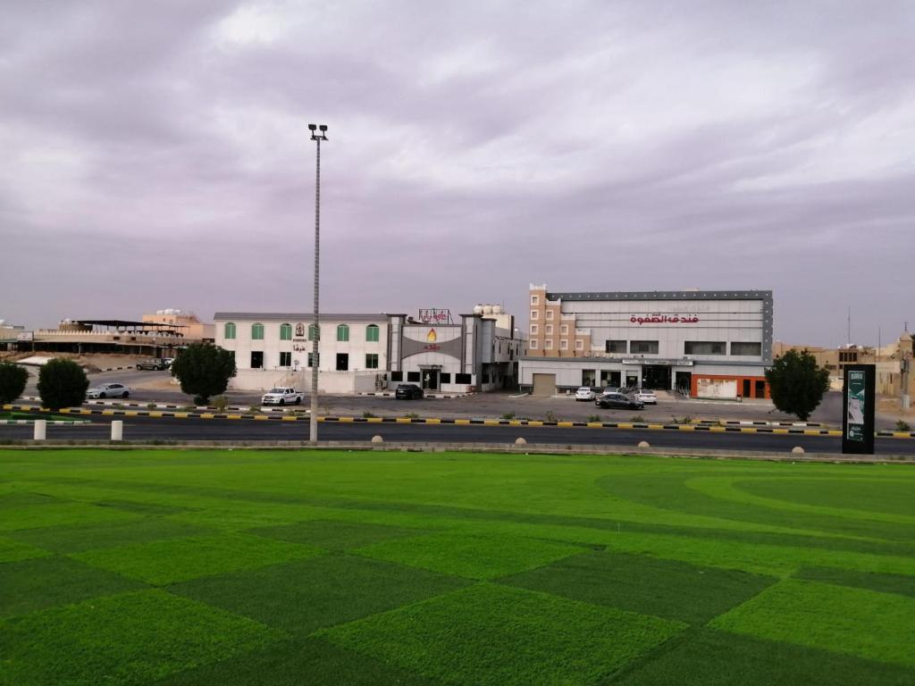 a green field with buildings and a parking lot at فندق قمم الصفوه الفندقيه in Rafha