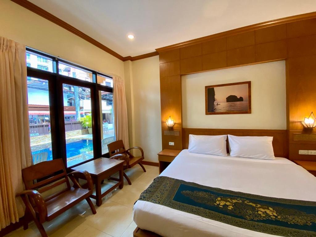 a bedroom with a bed and a chair and a window at Baan Sudarat Hotel in Patong Beach
