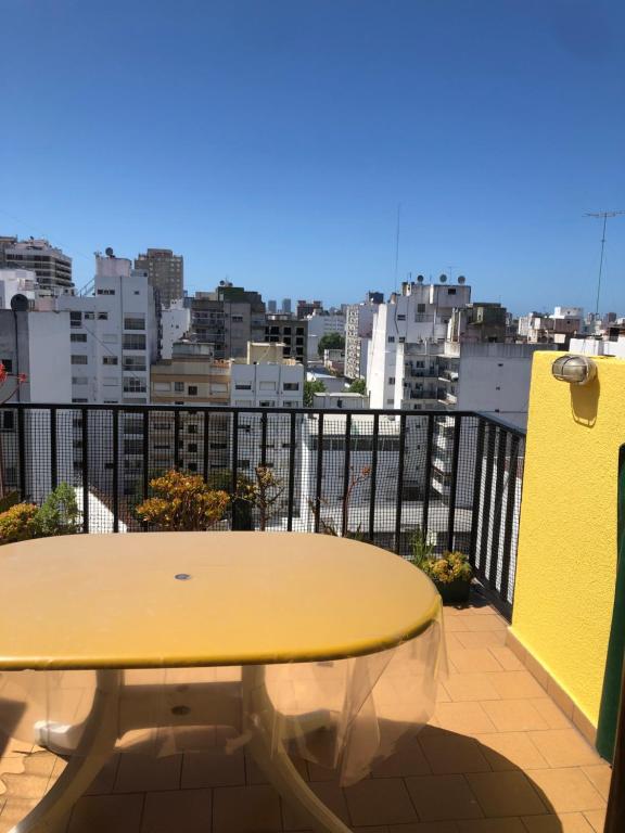 una mesa amarilla en un balcón con vistas a la ciudad en El Reino MdQ en Mar del Plata