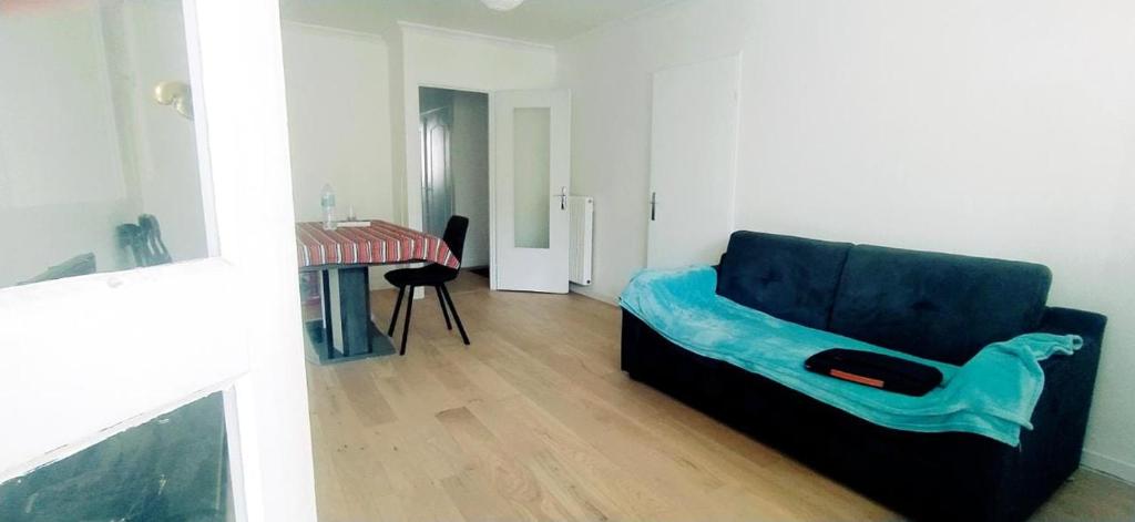 ein Wohnzimmer mit einem blauen Sofa und einem Tisch in der Unterkunft Chez Erwan & Elizabeth in Rennes