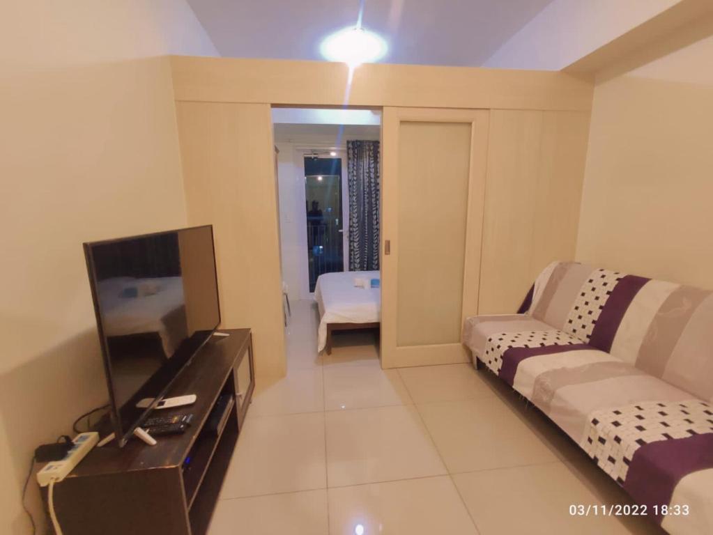 a living room with a couch and a flat screen tv at Jazz Residences (Destina Stays)Makati, Metro Manila in Manila