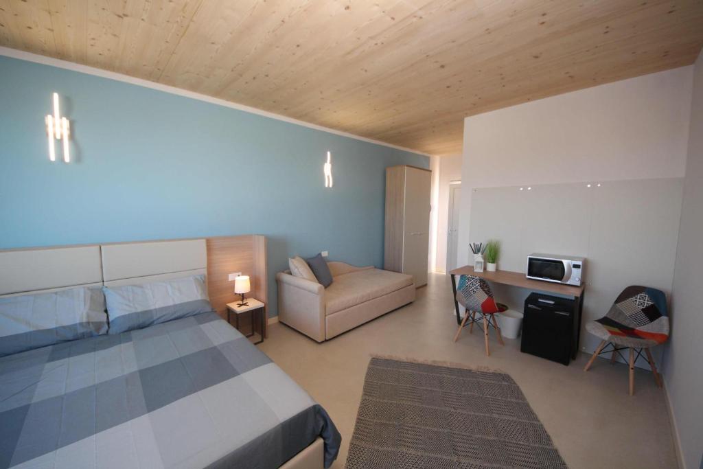 1 dormitorio con cama y sofá en Ohana Holiday Rooms, en Rosolina Mare