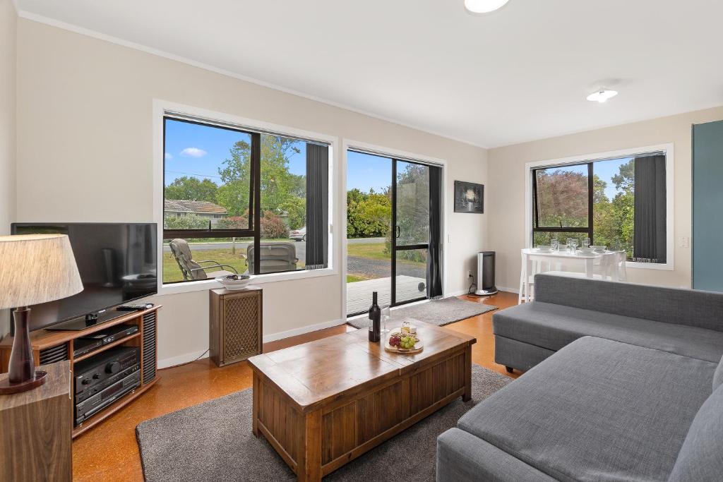 a living room with a couch and a table at Pipi Cabin - Mangawhai Village Bach in Mangawhai