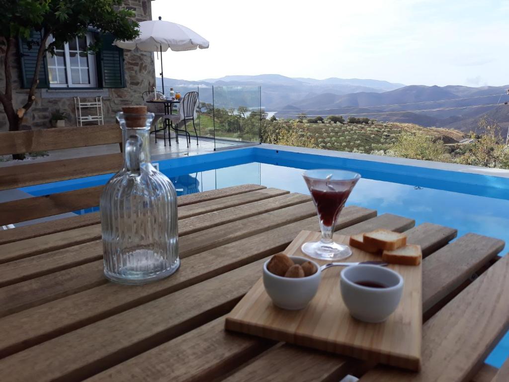 una mesa con una copa de vino y queso y una bebida en Casinha da Colina, en Alfândega da Fé