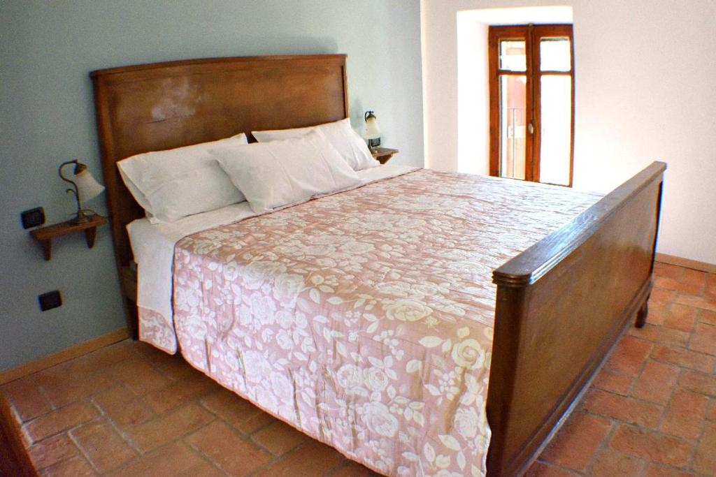 una camera con un grande letto con testiera in legno di b&b CASCINA SORTINA Country House a Ozzano Monferrato
