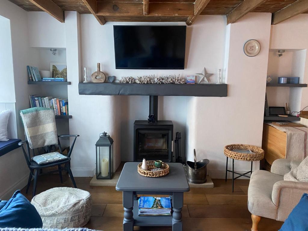 ein Wohnzimmer mit einem Kamin und einem Flachbild-TV in der Unterkunft Shrimp Cottage - 3 bed renovated cottage with stunning sea views in Staithes