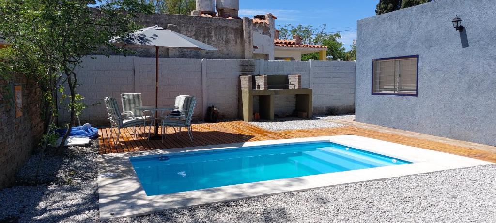 a small swimming pool with a table and an umbrella at Jazmin del Cielo in Capilla del Monte