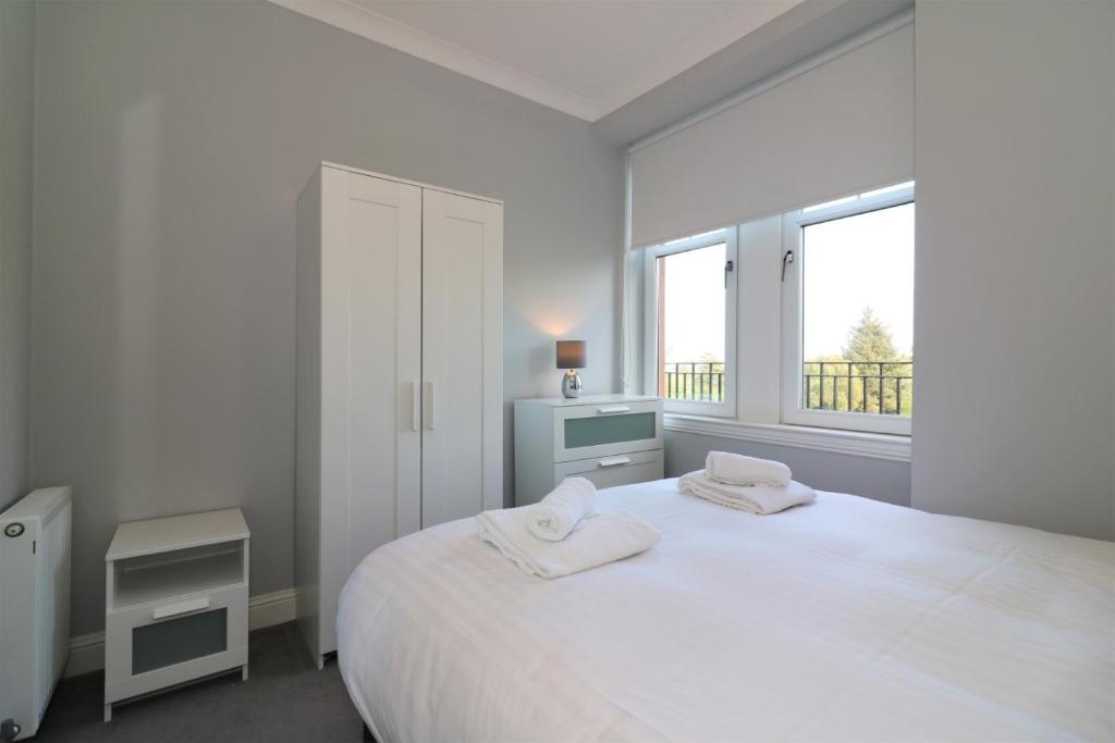 a white bedroom with a large bed with two towels on it at Signature - Greenlees Clubhouse in Glasgow