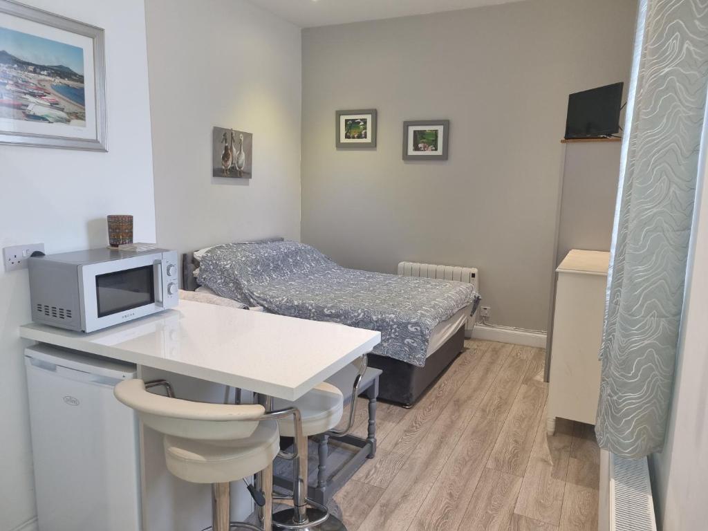 a small room with a bed and a desk with a microwave at Cracatinni Mews in Roundwood