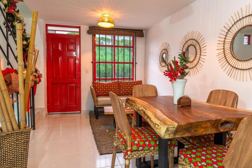a dining room with a wooden table and a red door at APARTAMENTO MI REFUGIO in Salento
