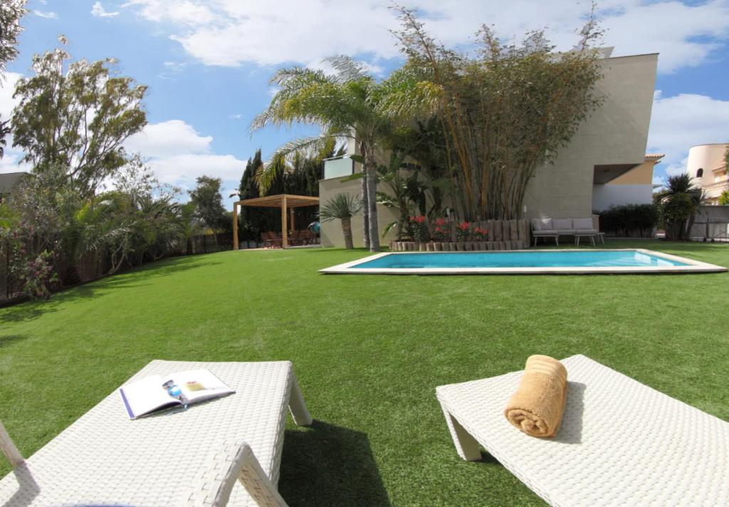 une cour avec deux bancs blancs et une piscine dans l'établissement VillaSpa, à Alcúdia