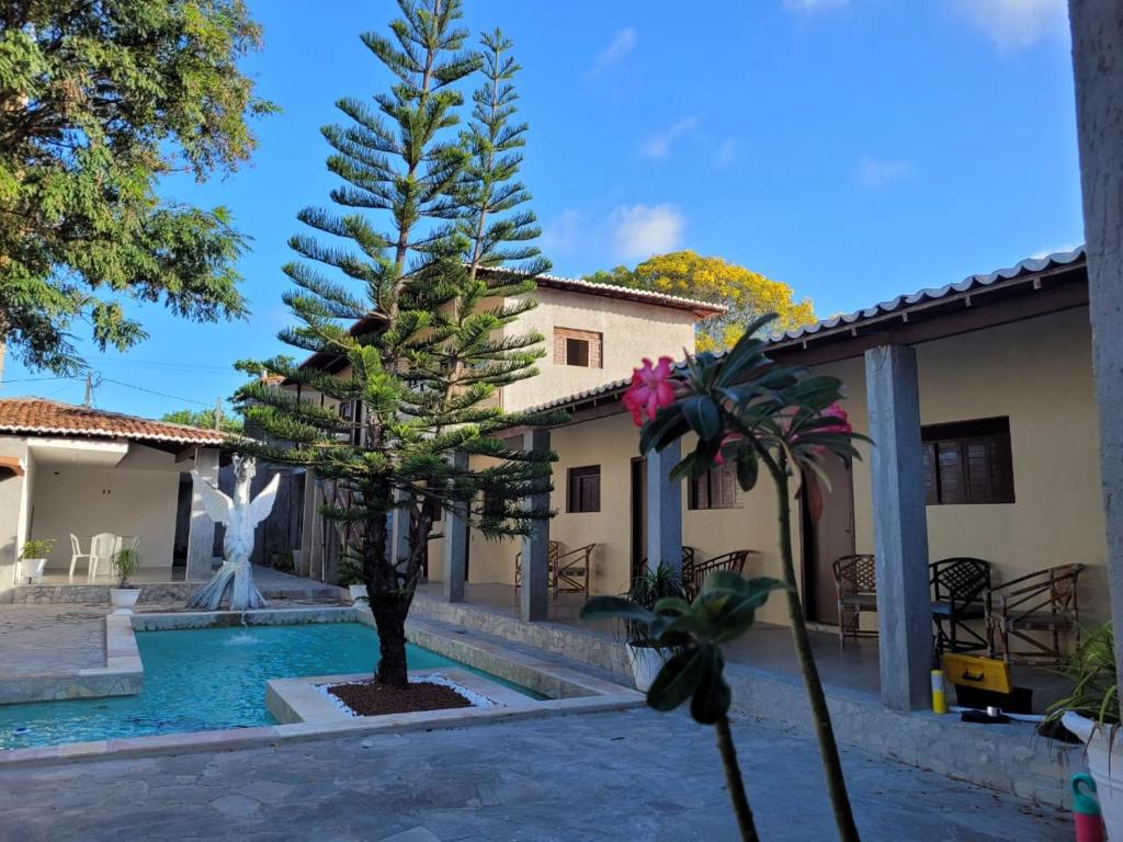 a courtyard with a swimming pool with a fountain and trees at Pousada Praia De Ponta Negra in Natal