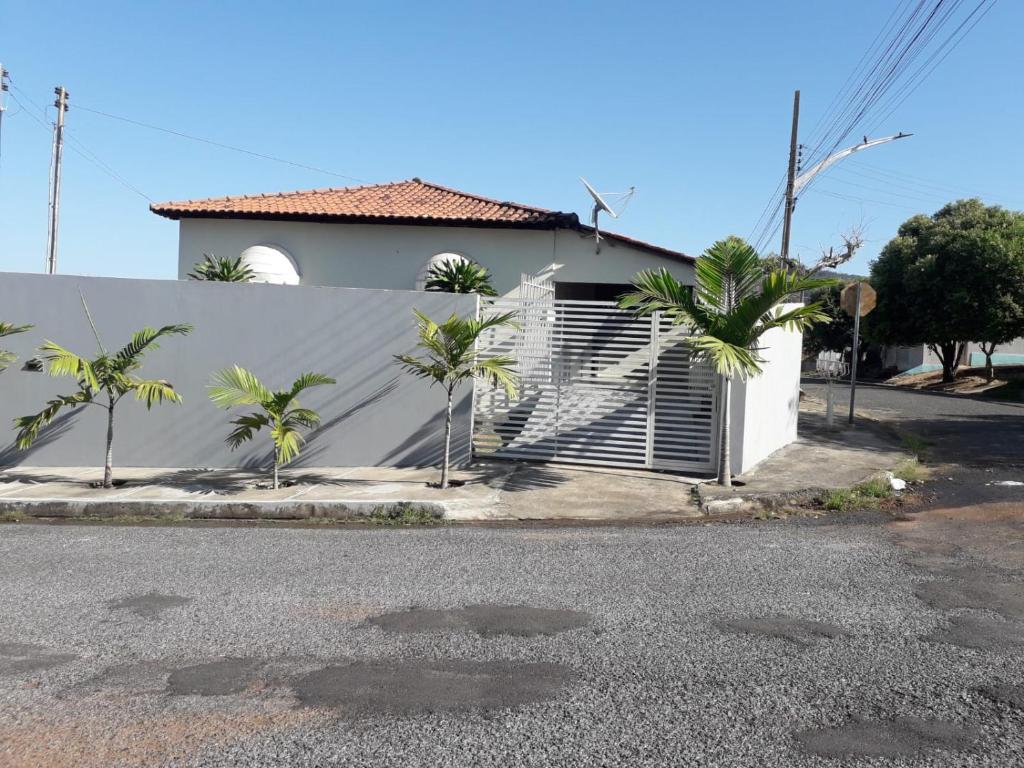 uma casa branca com palmeiras e uma cerca em Nosso Lar casa inteira, completa e independente em Barra do Garças