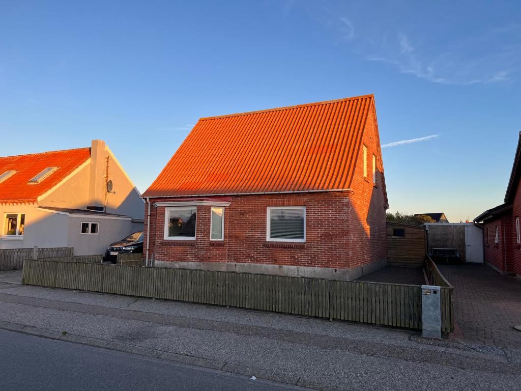 ein orangefarbenes überdachtes Haus mit orangefarbenem Dach in der Unterkunft Hyggeligt byhus in Harboør