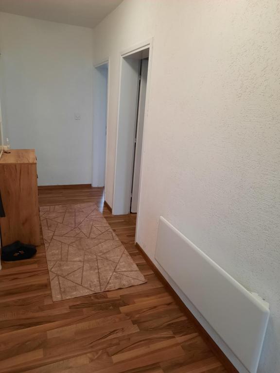 an empty room with a white wall and a wooden floor at apartman Magnolia in Sarajevo