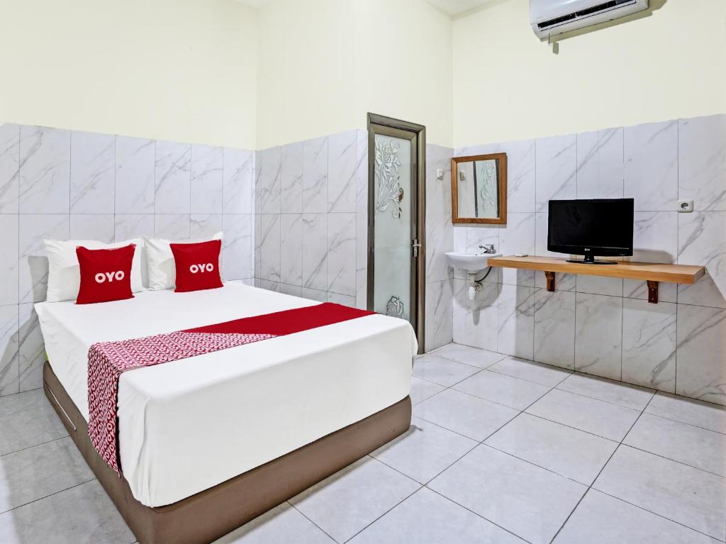 蘇達約縣的住宿－OYO Life 91884 Kost Kusuma Dewi Syariah，一间卧室配有一张带红色枕头的床和电视。