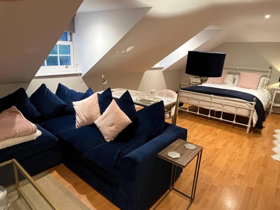 ein Wohnzimmer mit einem blauen Sofa und einem Bett in der Unterkunft The Pheasantry - guest house in beautiful rural location in Aldermaston