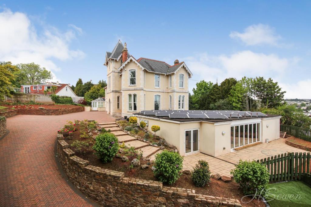 a large white house with a stone wall at Torbay Rise sea side villa with family facilities in Torquay