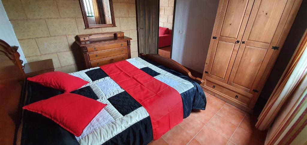 a bedroom with a bed with a red and blue quilt at Club JM Lanzarote in Tabayesco